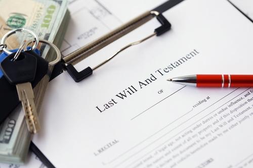 Pen and keys on Last will and testament form and planning blueprints of residential building project